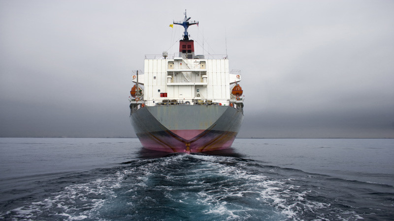 Stern of a grey and pink cargo ship.